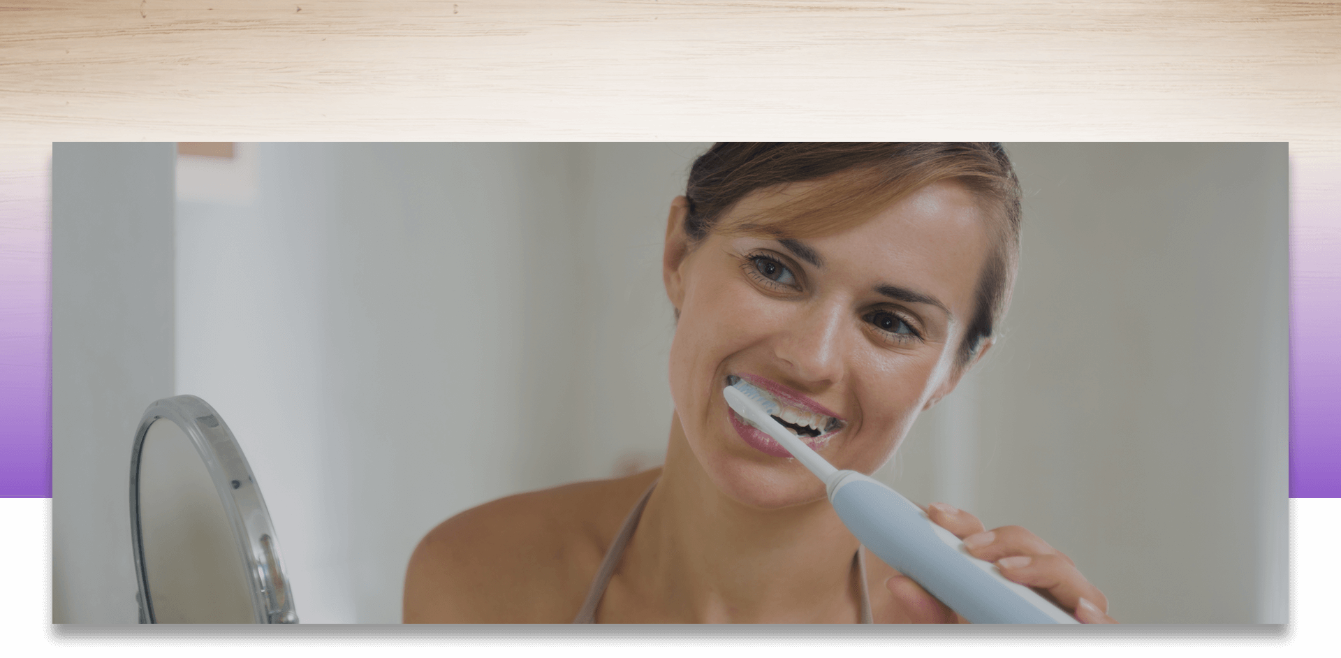 Smiling young woman brushing her teeth in front of a mirror